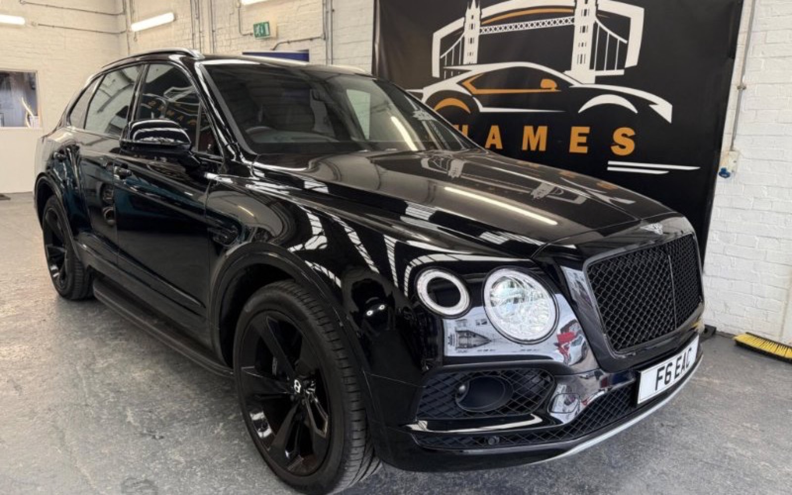 A black Bentley photographed inside the Thames Cars showroom beside the dealership banner